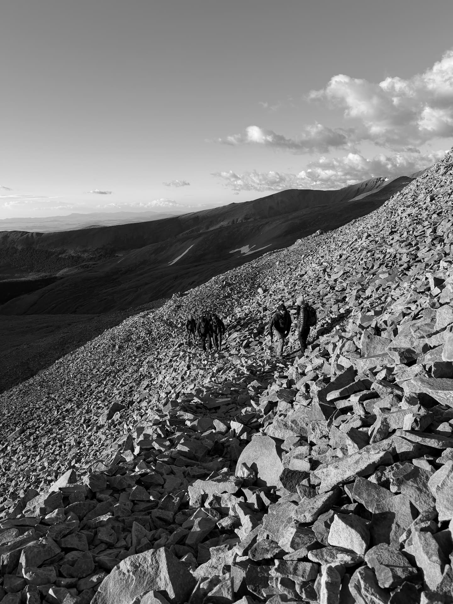 A No Matter What group climbing a steep scree slope at sunrise